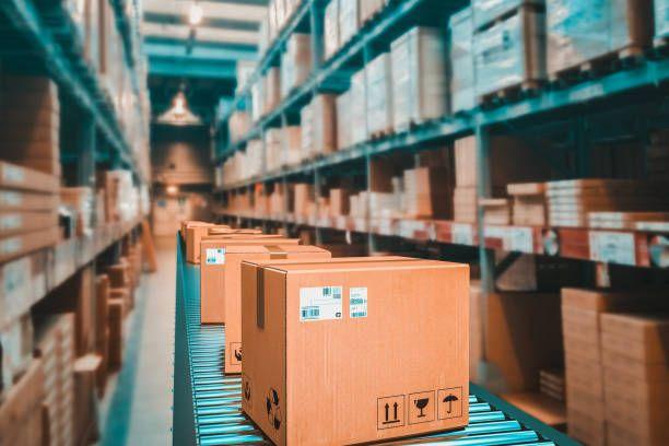 Caixas identificadas em uma esteira de movimentação dentro de um armazém logístico, representando processos de armazenagem e distribuição.